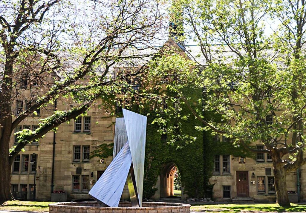 Quad with abstract statue and foliage in spring